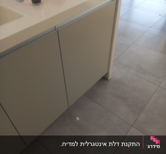 מטבח עם כלים על השיש, ארונות ורצפה מרוצפת